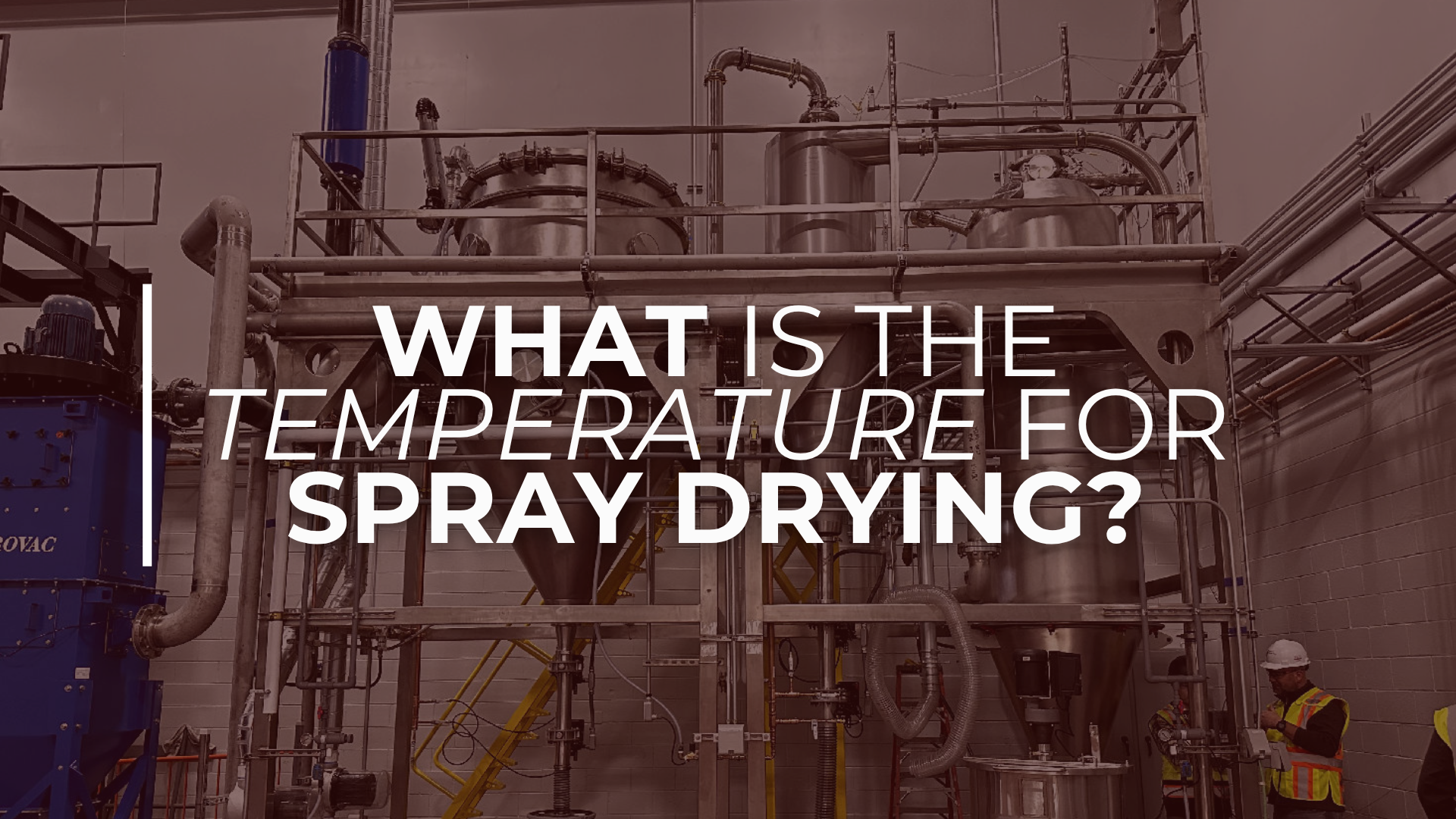 Industrial spray drying system with stainless steel vessels and pipes inside a production facility, featuring the text “What is the temperature for spray drying?”