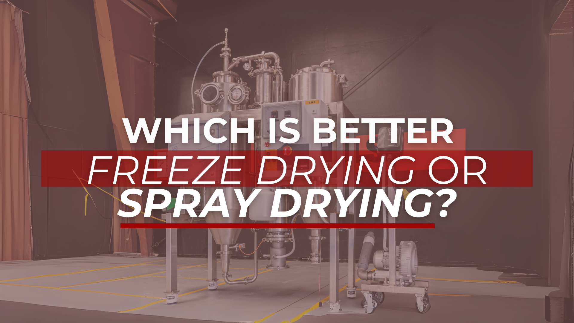 Industrial spray drying equipment inside a manufacturing facility with large metal vessels and pipes. The foreground features a bold headline overlay in white and red text: “Which is better: Freeze Drying or Spray Drying?”—visually highlighting a key processing equipment comparison topic.