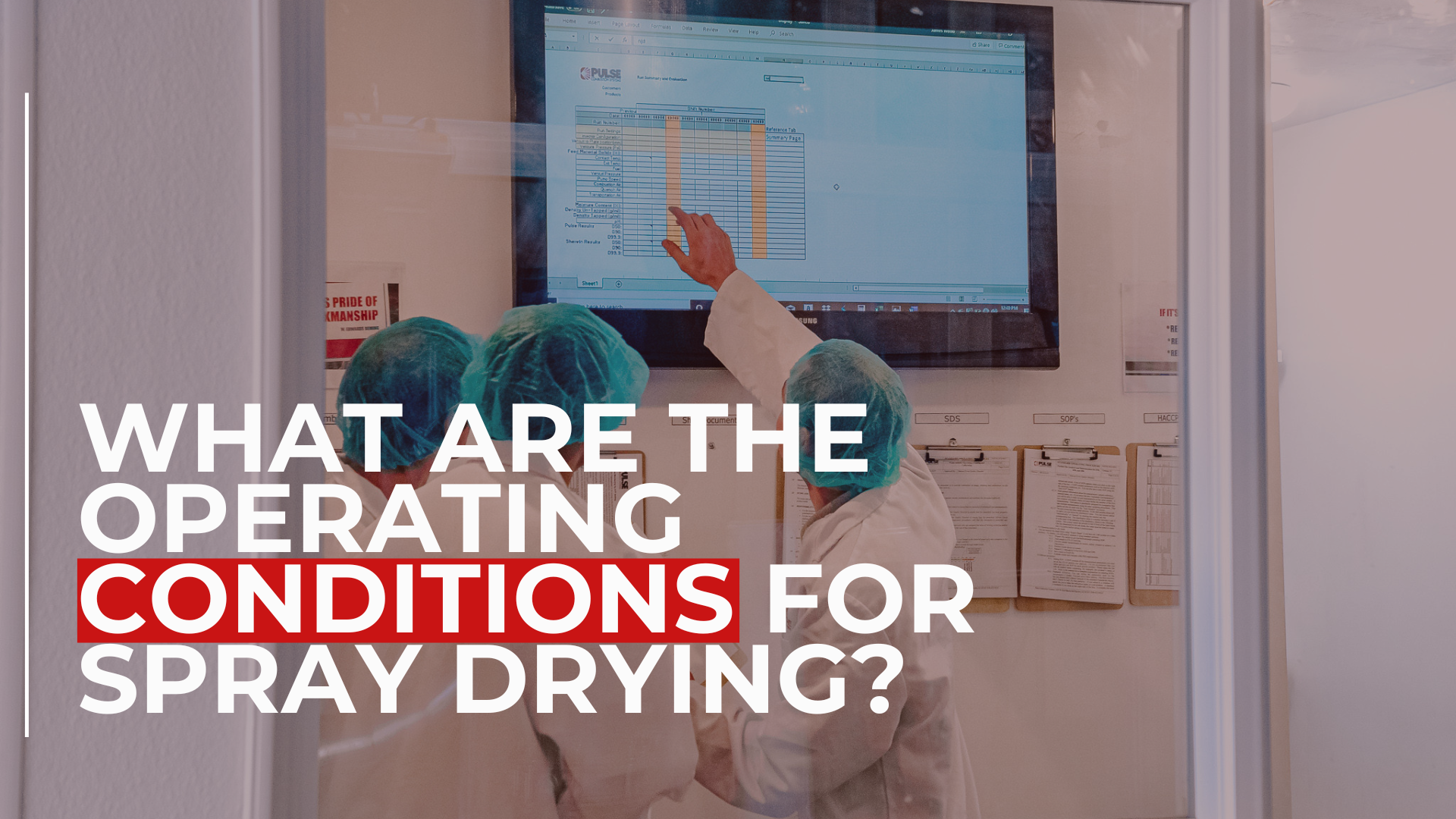 Lab technicians in protective gear analyze data on a large screen in a controlled environment, with overlaid text reading, “What are the operating conditions for spray drying?”